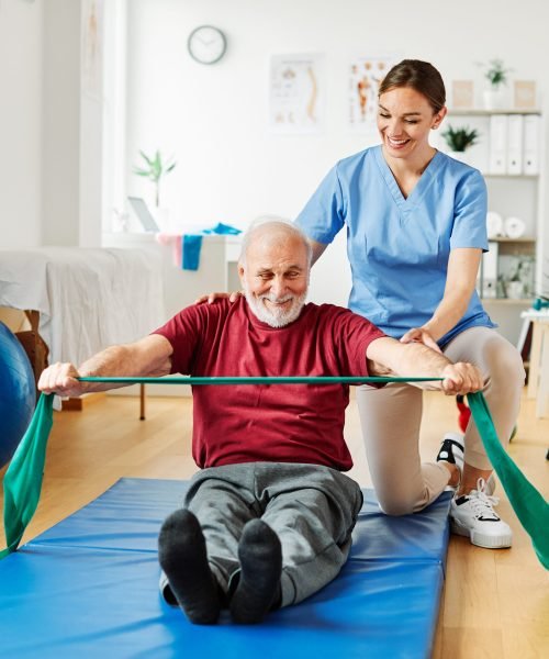 Doctor or nurse caregiver exercise with senior man at clinic or nursing home
