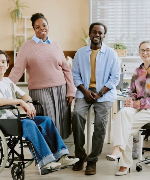 Portrait of young international IT team sitting for photo in center of light and comfort office of modern IT company